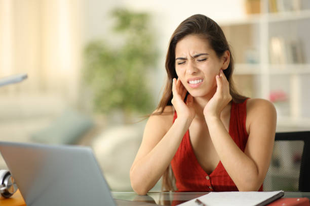 Mujer con dolor mandibular por bruxismo apretando la mandíbula con las manos